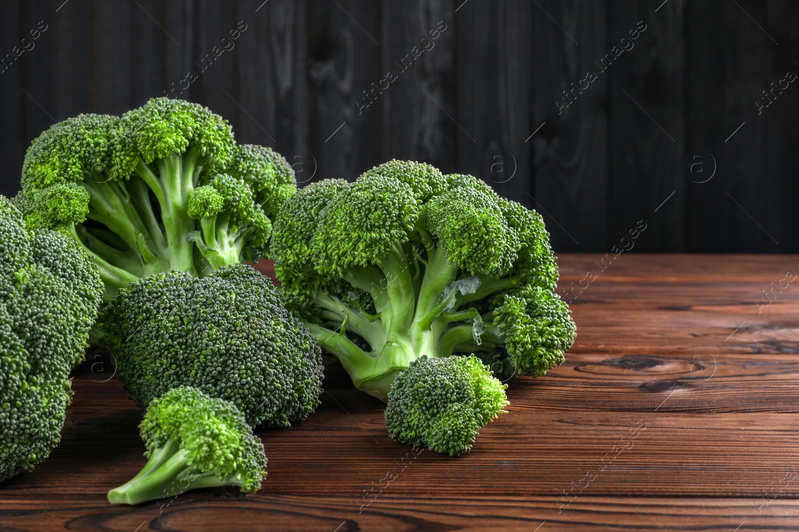 Photo of Fresh raw broccoli on wooden table, closeup. Space for text