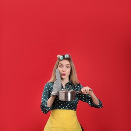 Photo of Young housewife with saucepan on red background