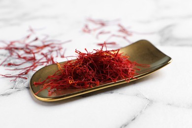 Photo of Dried saffron on white marble table, closeup