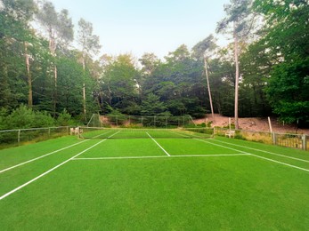 Tennis court with green grass and net outdoors