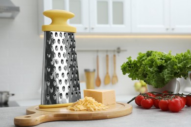 Photo of Grater, cheese and vegetables on table in kitchen