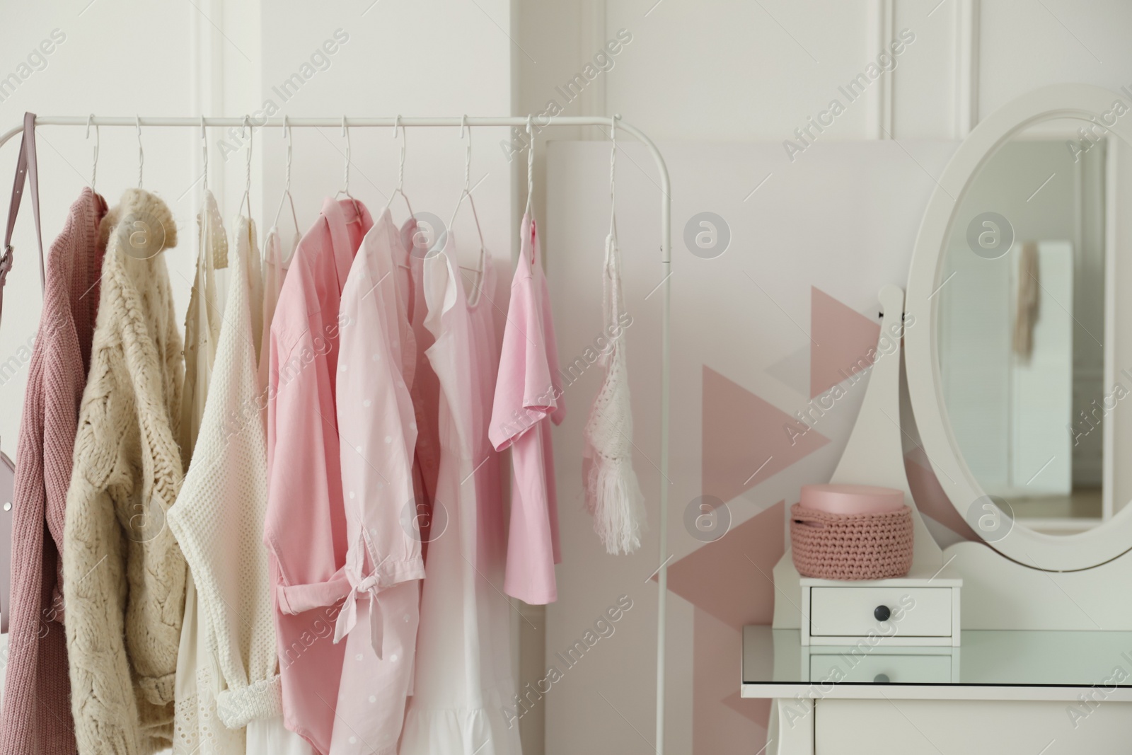 Photo of Dressing room interior with clothing rack and round mirror
