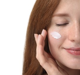 Beautiful woman with freckles and cream on her face against white background