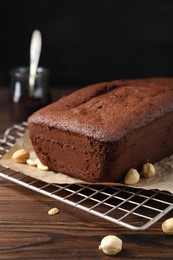 Delicious chocolate sponge cake and nuts on wooden table, closeup