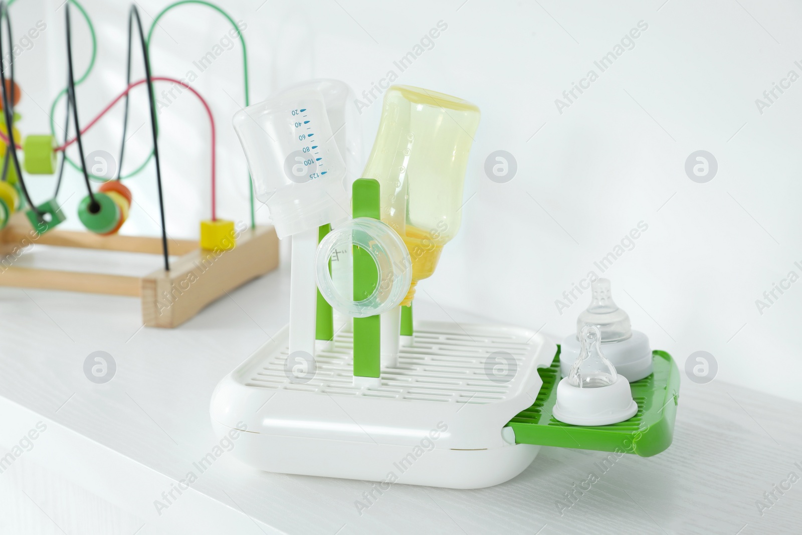 Photo of Dryer with baby bottles and nipples after sterilization on white table