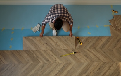 Professional worker installing new parquet flooring indoors, top view