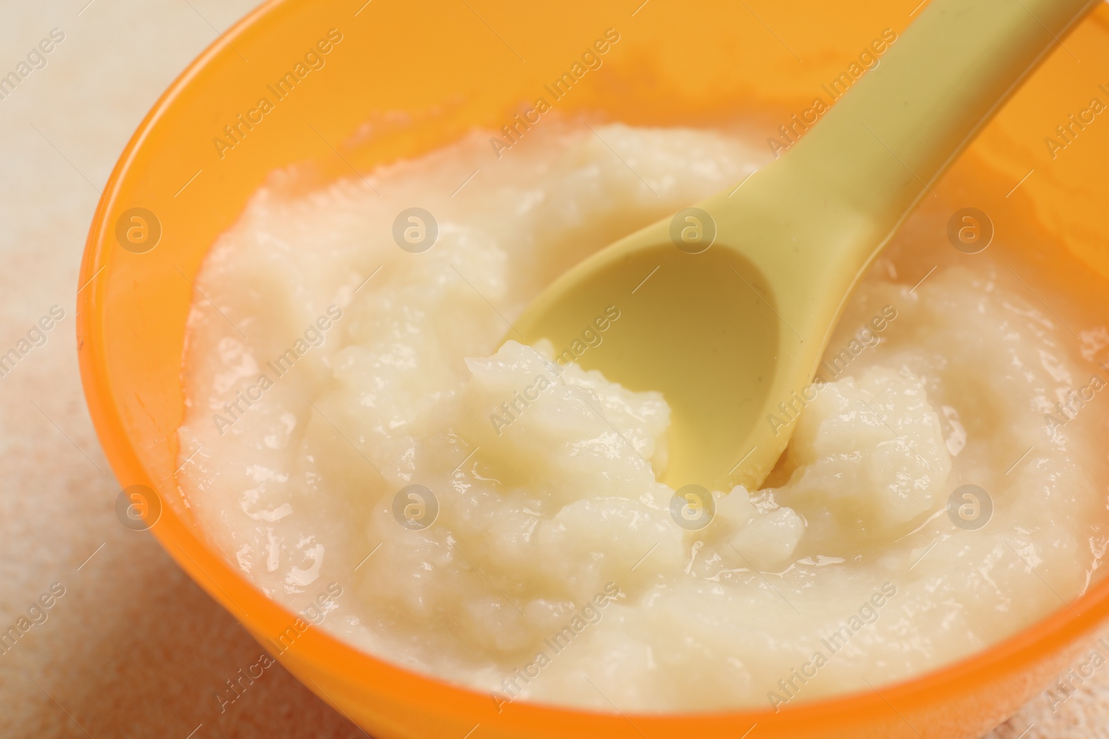 Photo of Baby food. Bowl with cauliflower puree on beige textured table, closeup