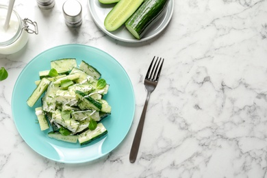 Photo of Plate with delicious cucumber salad served on marble table, top view. Space for text