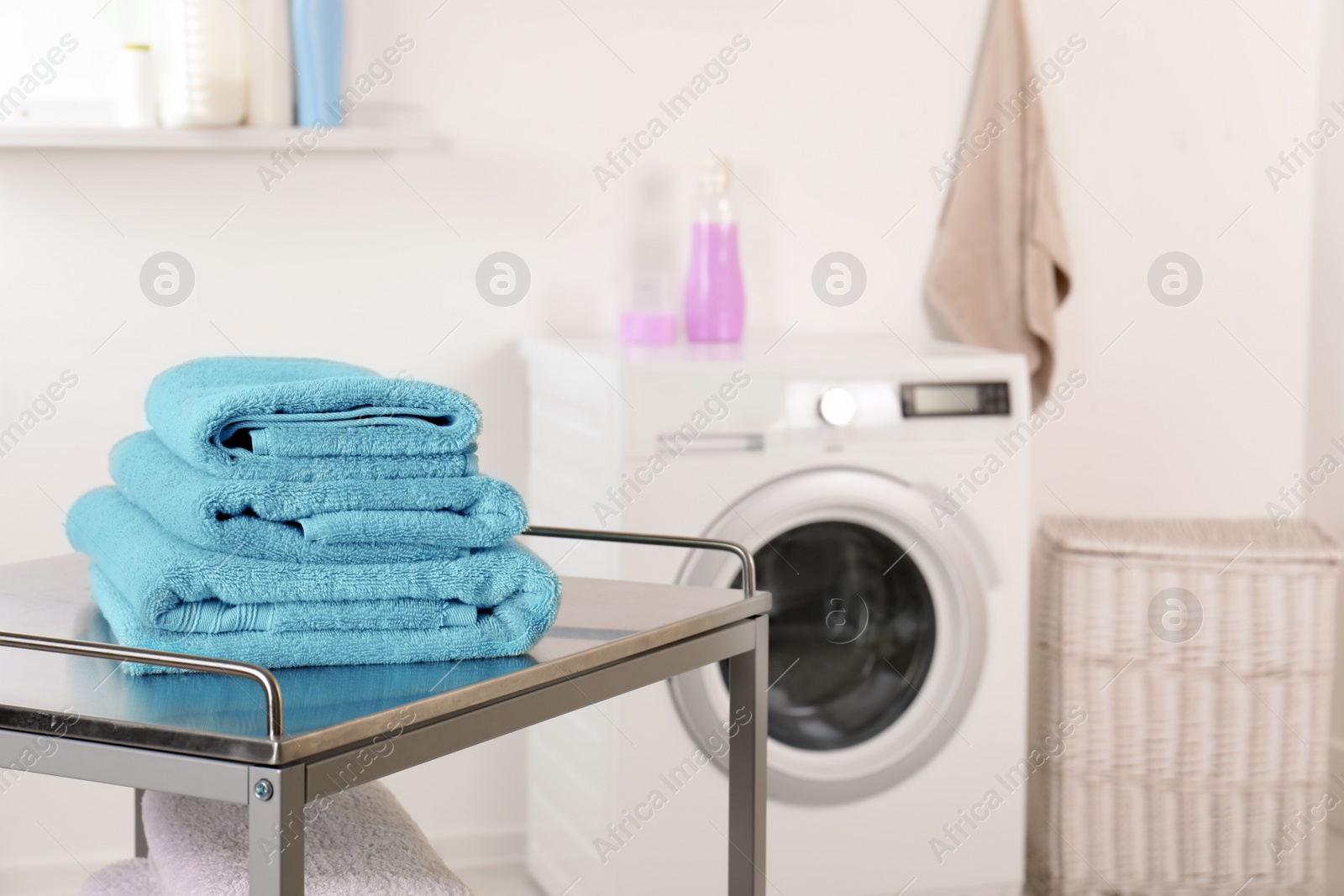 Photo of Stack of clean soft towels on table in laundry room. Space for text