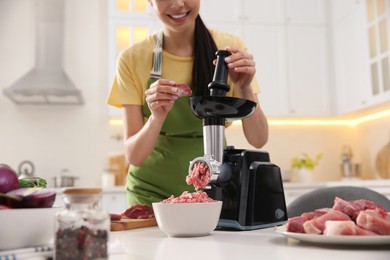 Photo of Young woman using modern meat grinder in kitchen, closeup