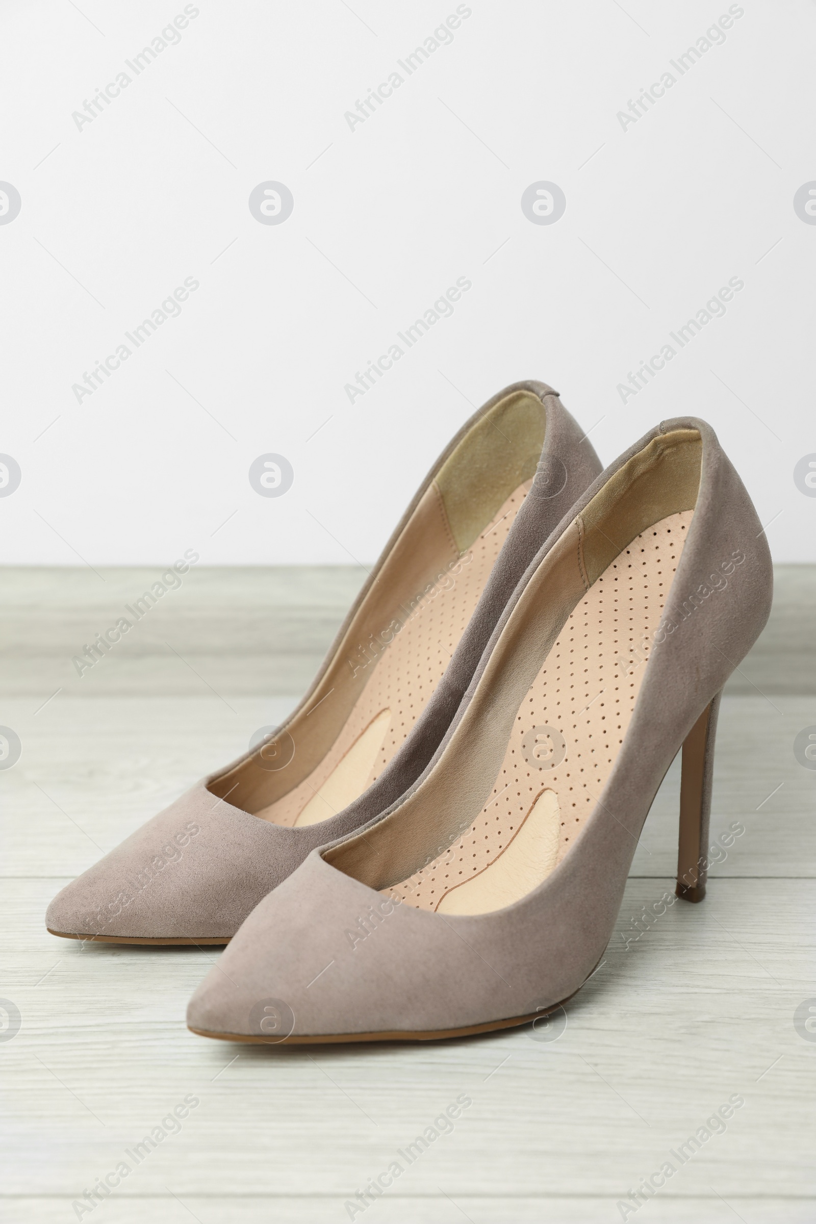 Photo of Orthopedic insoles in high heel shoes on floor