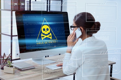 Image of Office worker in front of computer with warning about virus attack on screen