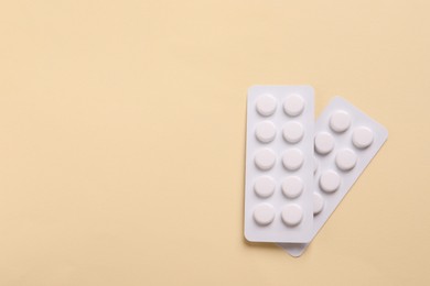 Photo of White pills in blisters on beige background, top view. Space for text