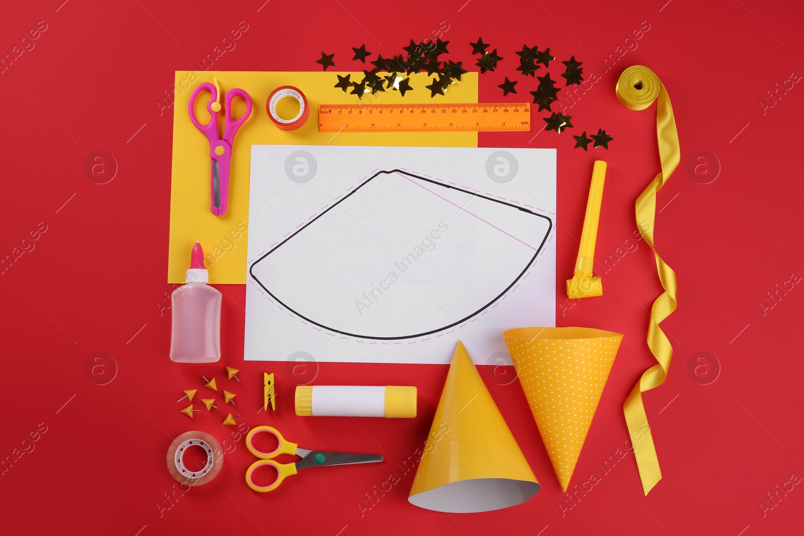 Photo of Handmade party hat template and supplies on red background, flat lay