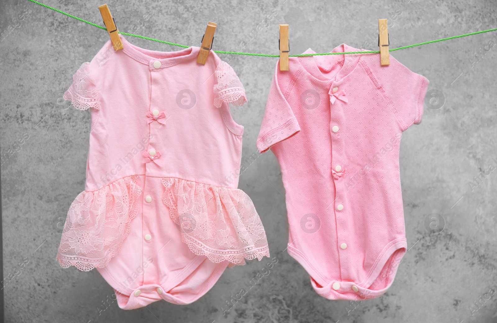 Photo of Baby clothes hanging on washing line against gray background