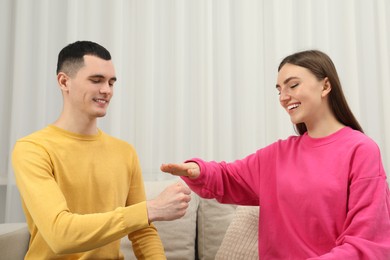 Happy people playing rock, paper and scissors in room