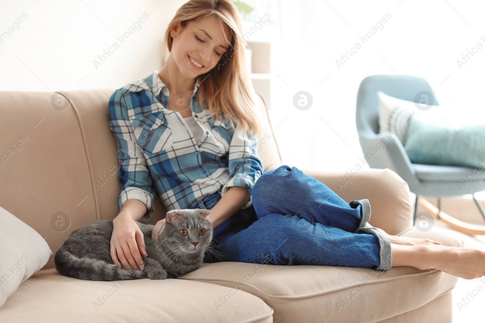 Photo of Young woman with her cute pet cat on sofa at home