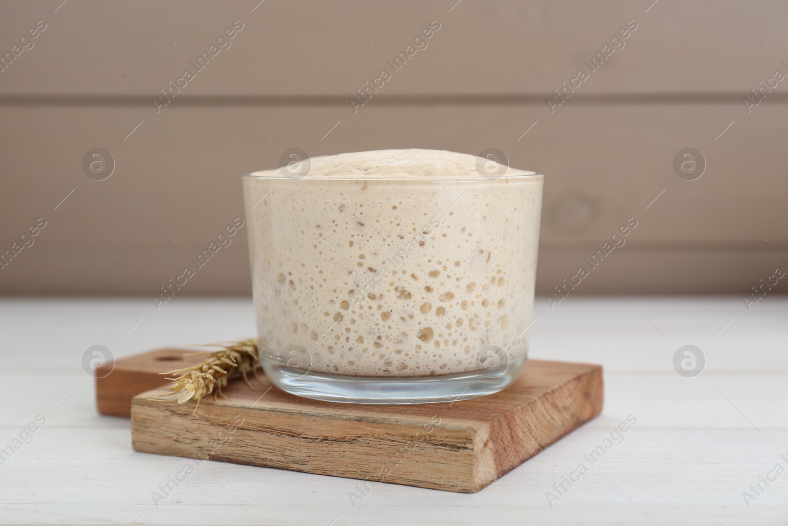 Photo of Leaven and ear of wheat on white wooden table