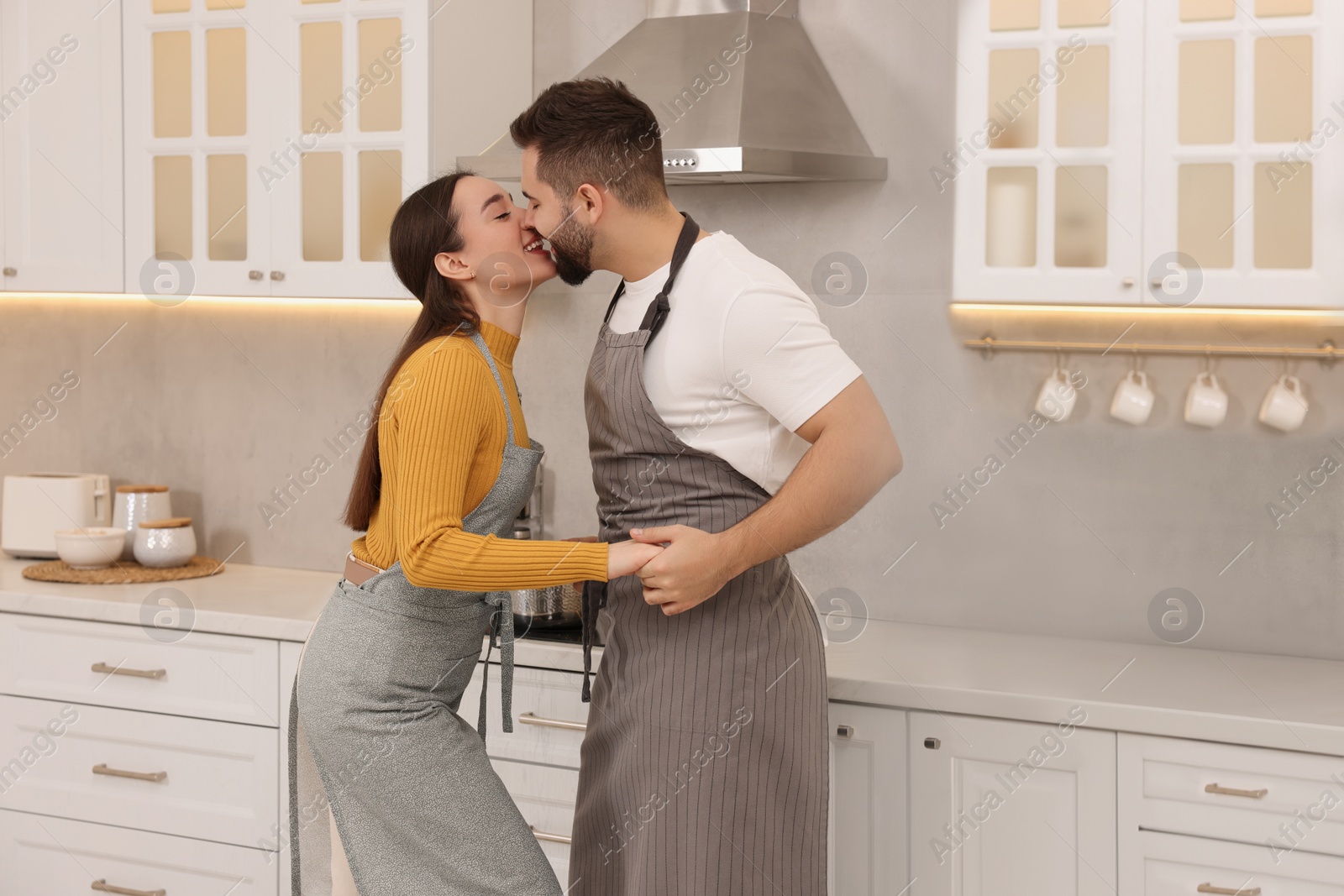 Photo of Happy lovely couple kissing together in kitchen