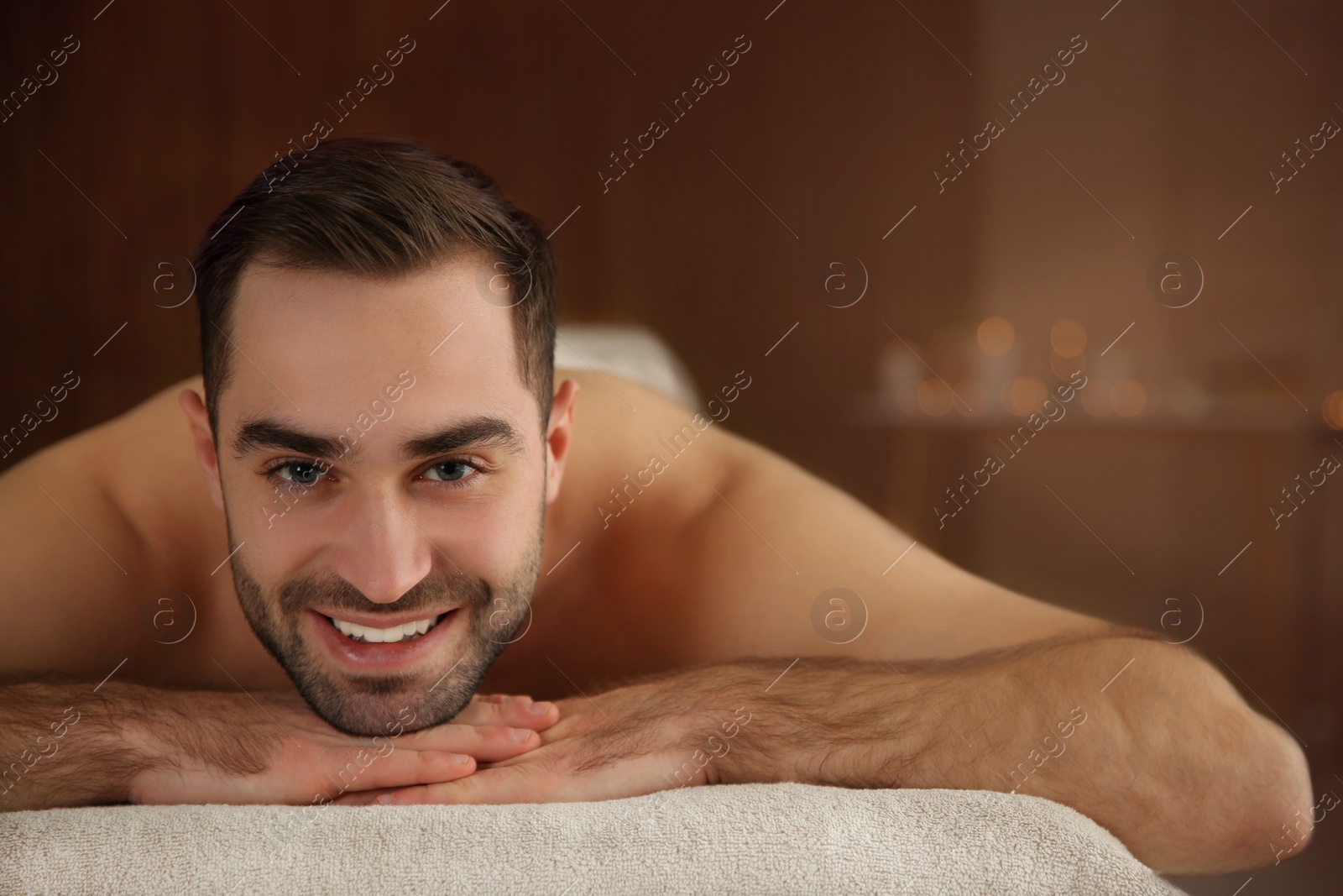 Photo of Handsome man relaxing on massage table in spa salon