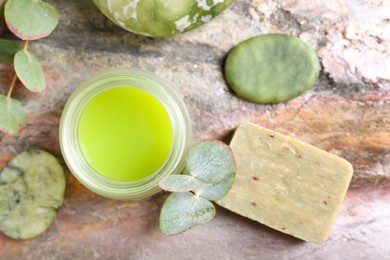 Photo of Jar of cream, spa stones, soap and eucalyptus branches on textured table, flat lay. Body care product