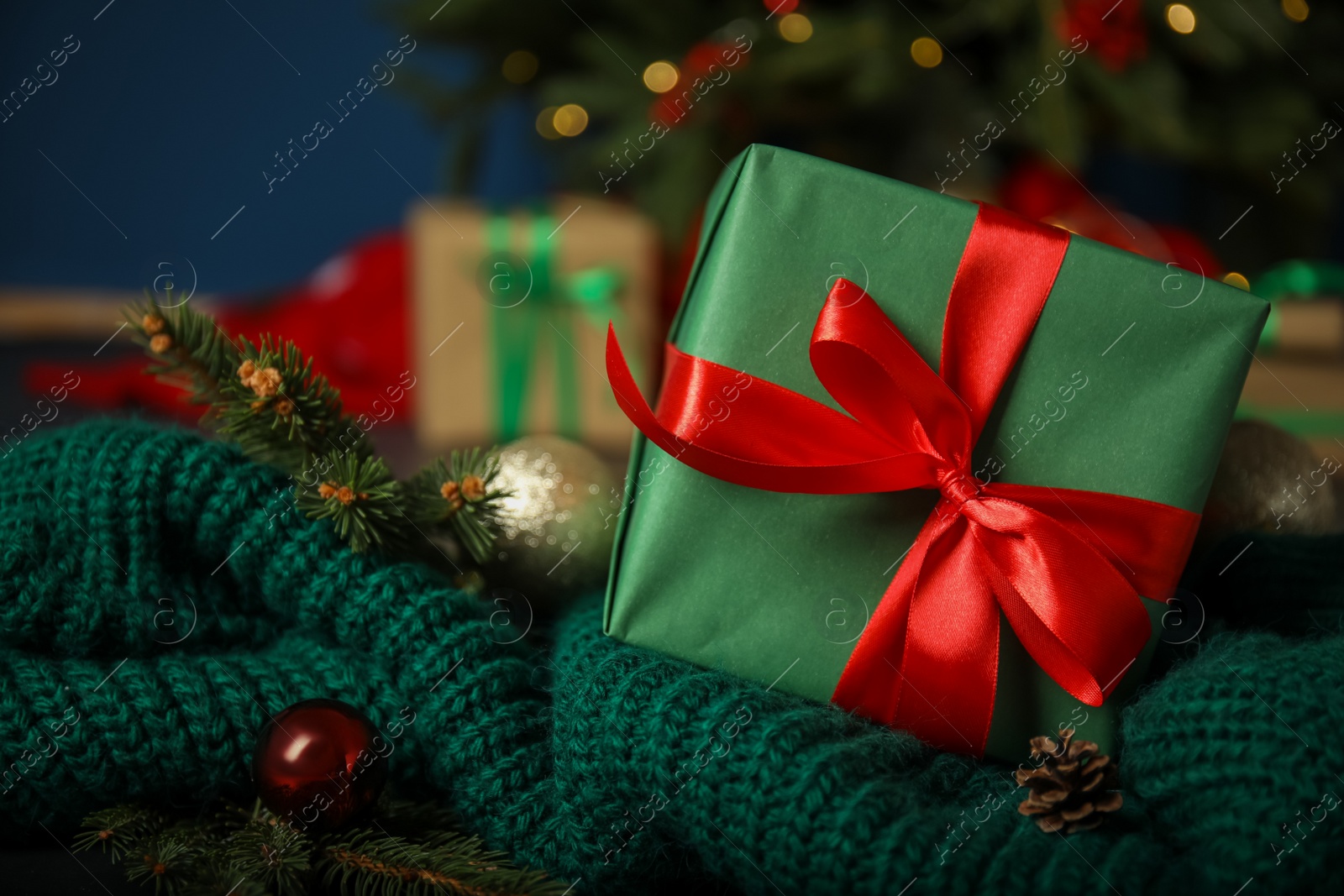 Photo of Beautiful Christmas gift box on green knitted fabric, closeup