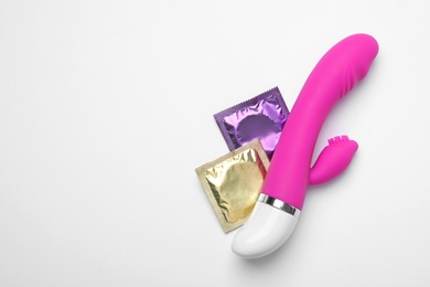 Photo of Vibrator and condoms on white background, top view. Sex game