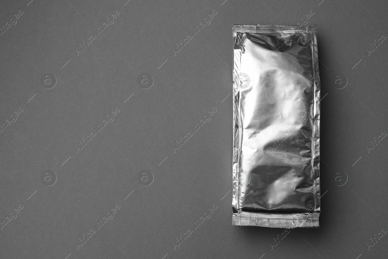 Photo of Blank foil package on grey background, top view. Space for text