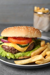 Photo of Delicious burger and french fries served on grey table, closeup