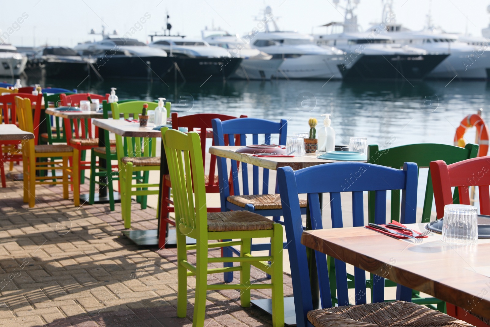 Photo of Beautiful view of outdoor cafe with colorful wooden chairs near pier