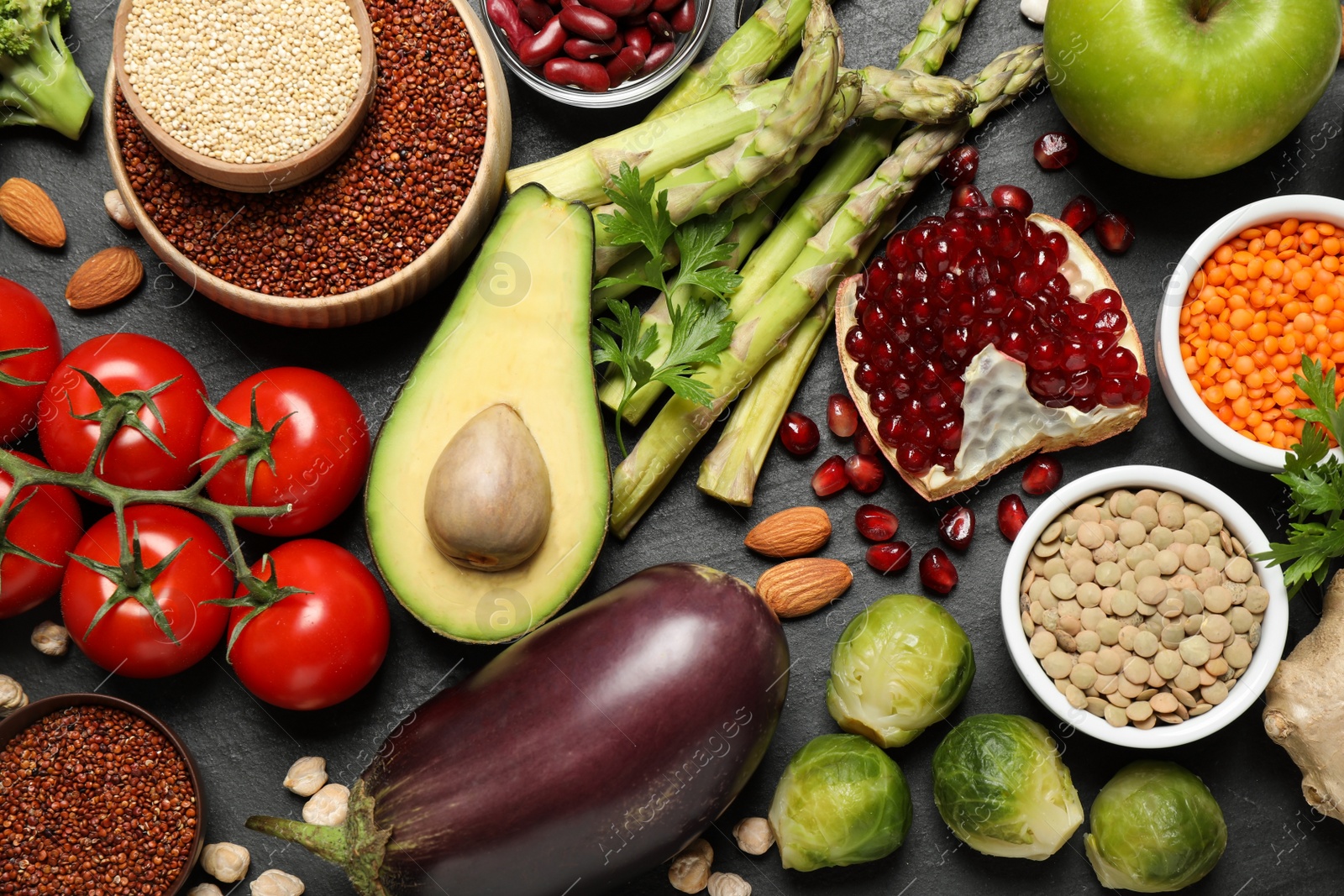 Photo of Fresh vegetables, fruits and seeds on black table, flat lay