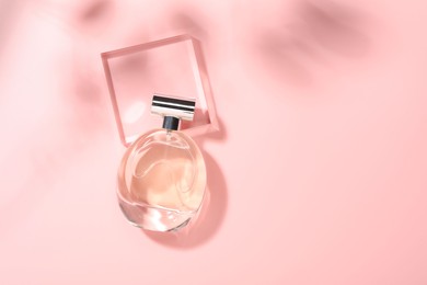 Photo of Bottle of luxury women's perfume in sunlight on pink background, top view. Space for text