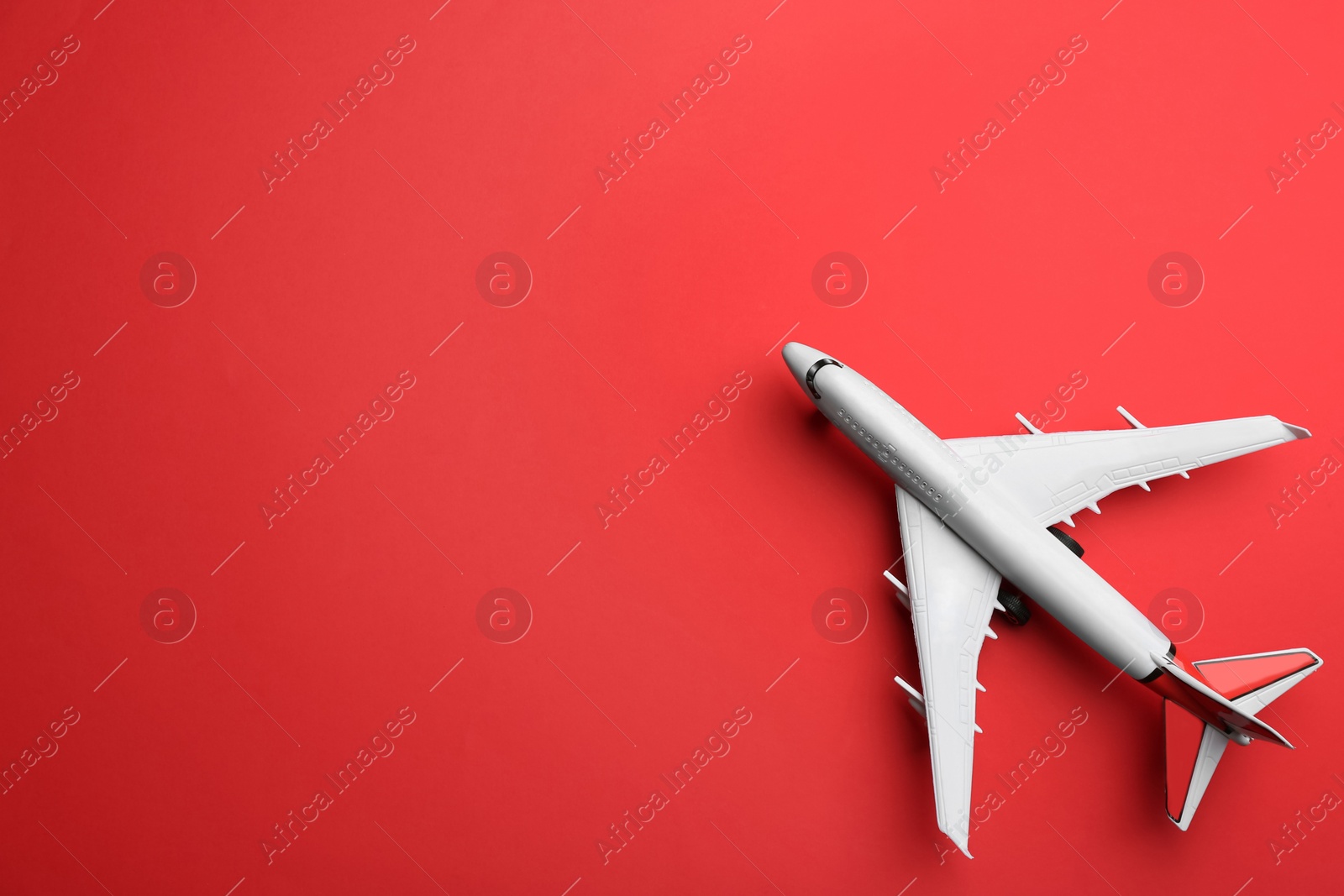 Photo of Toy airplane on red background, top view. Space for text