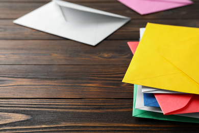 Photo of Colorful paper envelopes on wooden background, closeup. Space for text