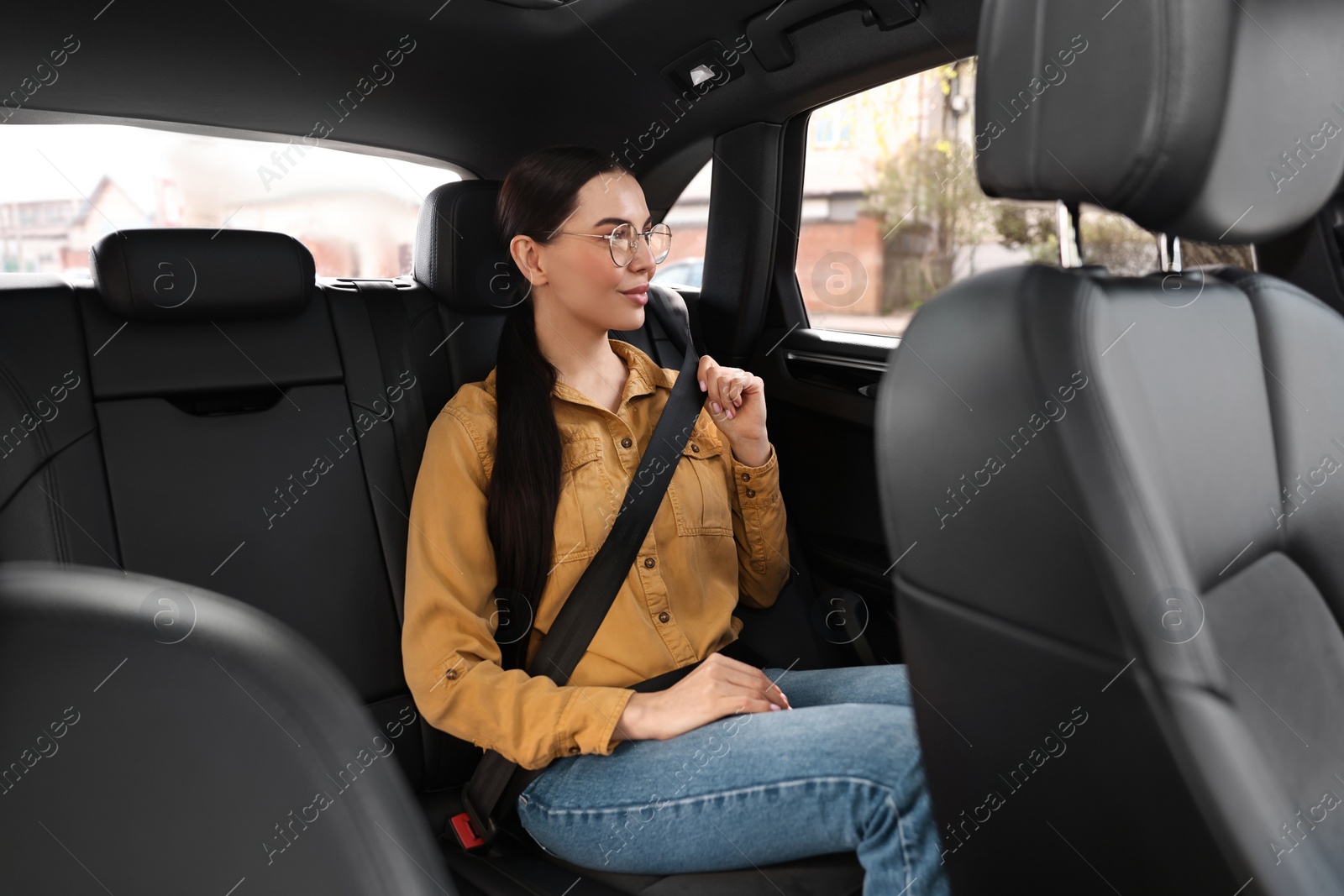 Photo of Woman fastening safety seat belt inside modern car