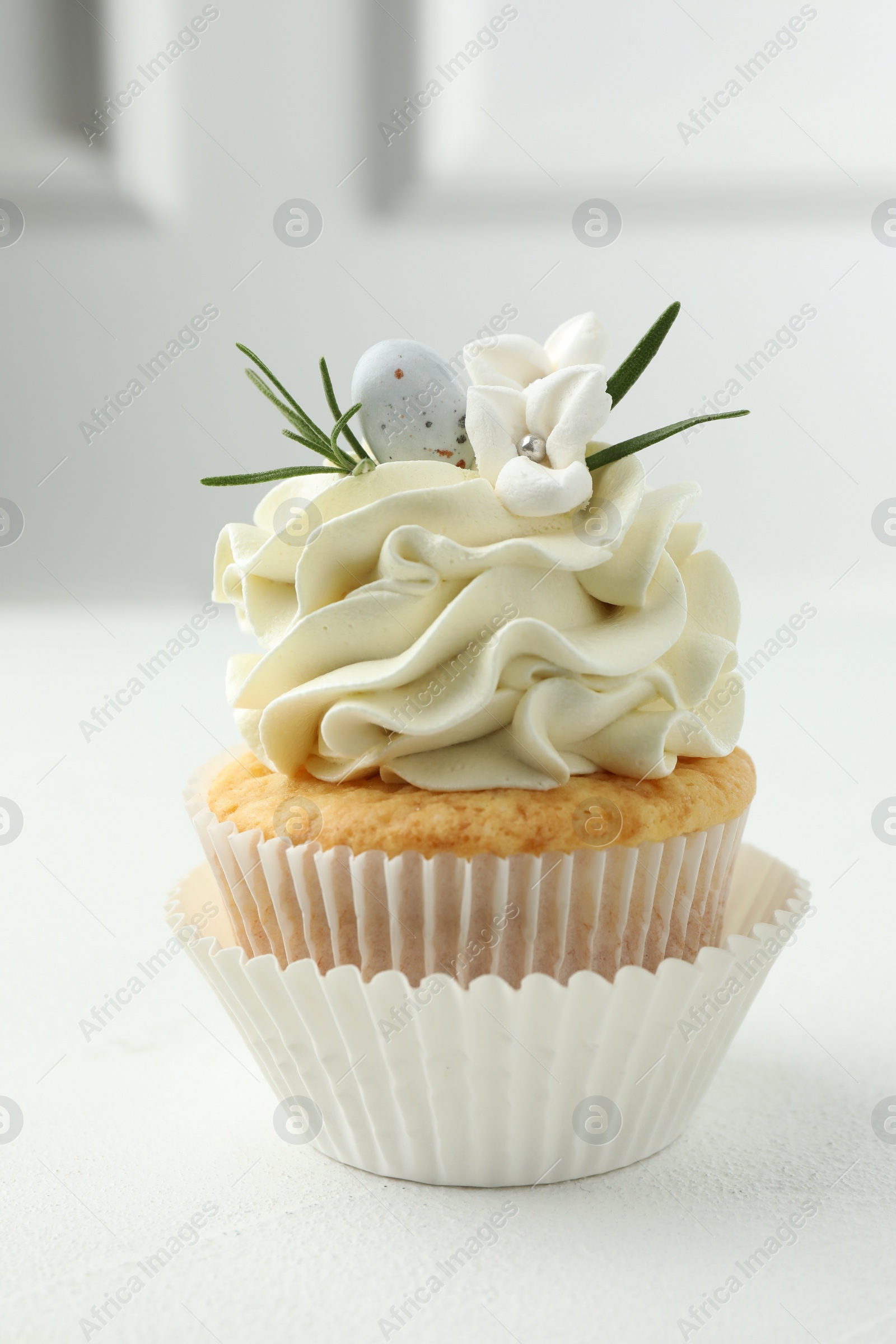 Photo of Tasty Easter cupcake with vanilla cream on white table