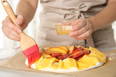 Woman making peach pie at kitchen table, closeup