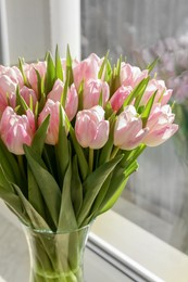 Spring is coming. Bouquet of beautiful tulip flowers in glass vase on windowsill indoors