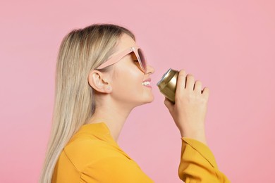 Photo of Beautiful happy woman drinking from beverage can on pink background