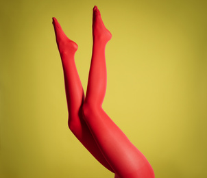 Photo of Woman wearing red tights on yellow background, closeup of legs