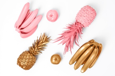 Photo of Composition with gold and pink fruits on white background, top view