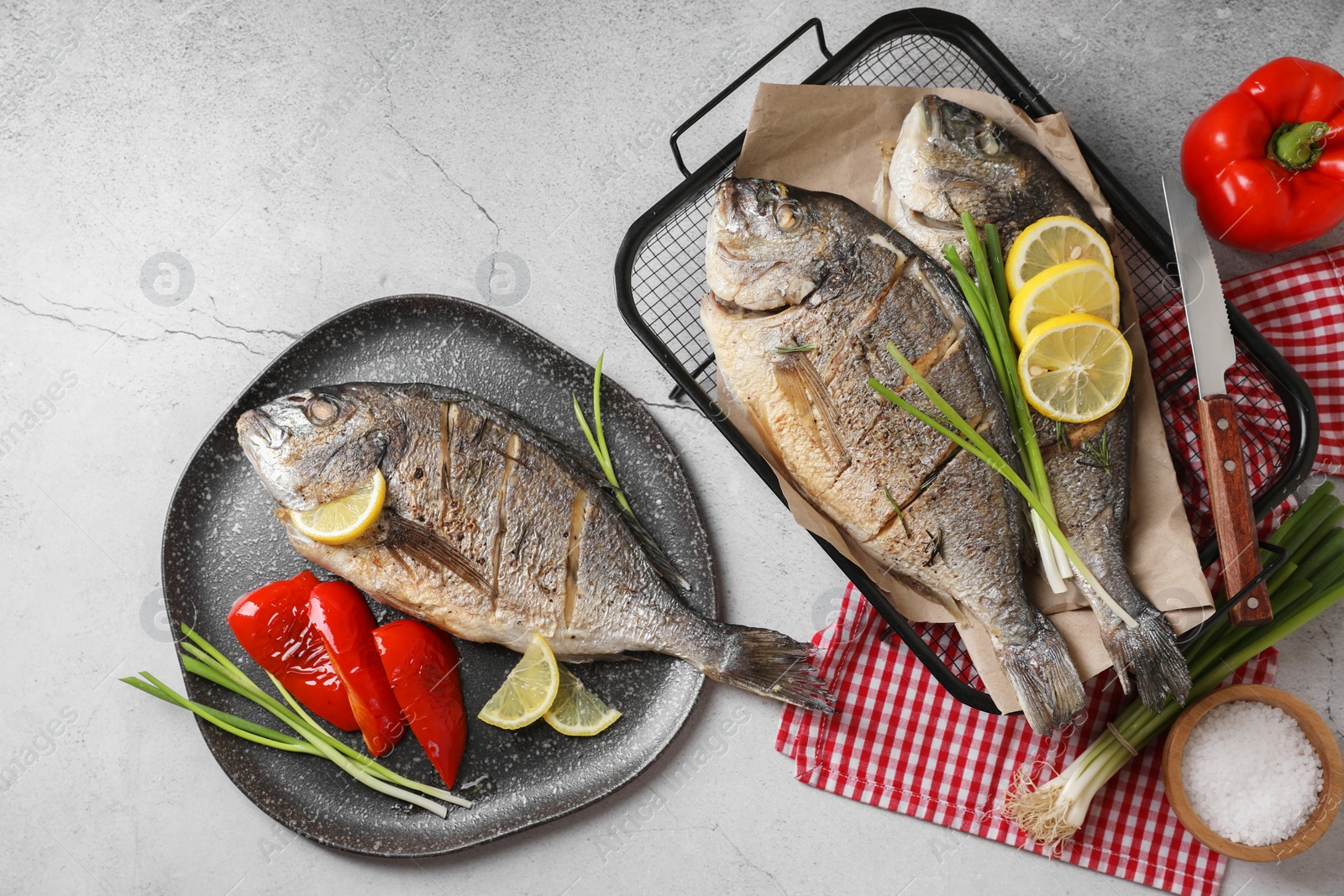 Photo of Seafood. Delicious baked fish served with green onion, bell pepper and lemon on light textured table, flat lay