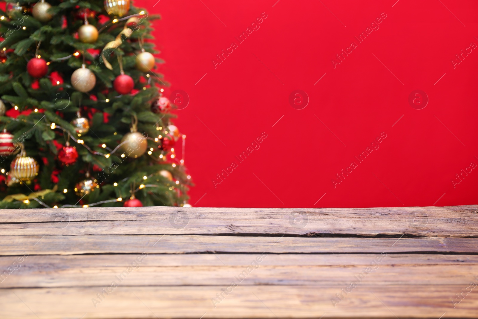 Photo of Wooden table and blurred Christmas tree with fairy lights on background