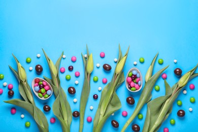 Photo of Flat lay composition with tulips and candies on light blue background, space for text. Easter celebration