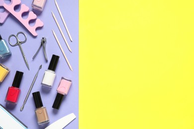 Photo of Nail polishes and set of pedicure tools on color background, flat lay. Space for text