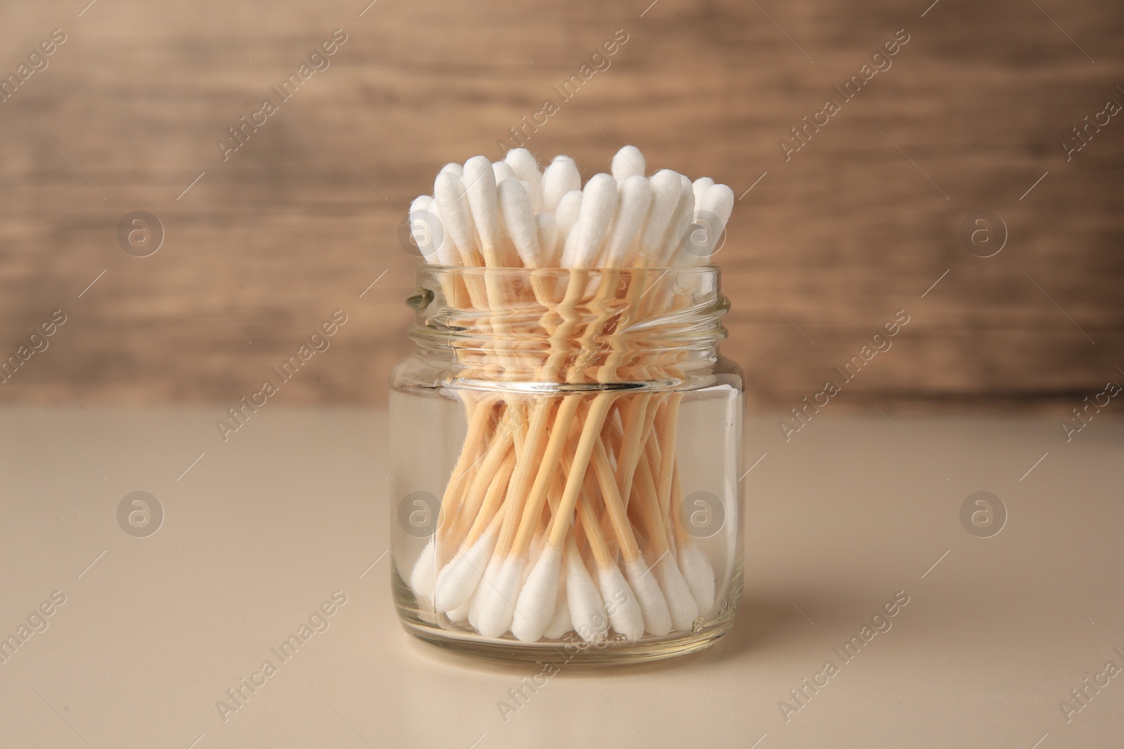 Photo of Jar of clean cotton buds on beige background