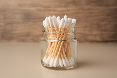 Photo of Jar of clean cotton buds on beige background