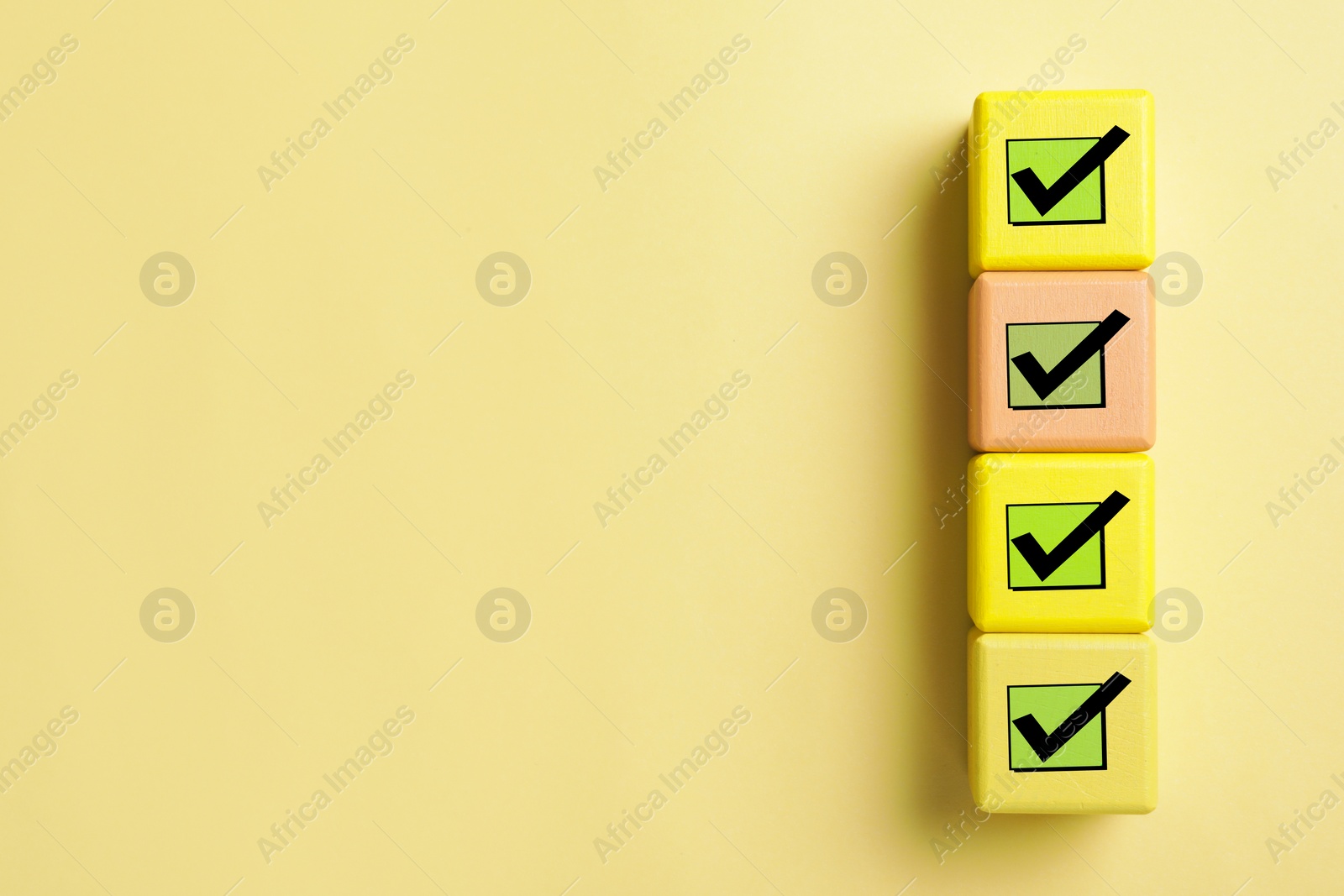 Image of Cubes with check marks on yellow background, top view. Space for text