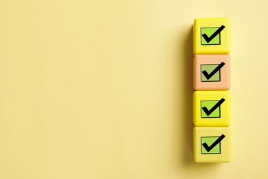 Cubes with check marks on yellow background, top view. Space for text