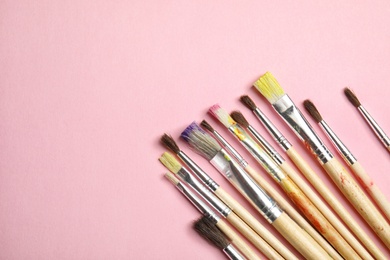 Different paint brushes on color background, top view with space for text